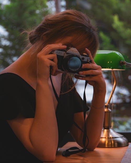 Woman Sitting at a Desk and Using a Camera 