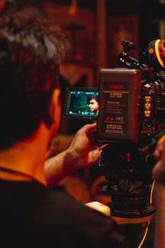 A cinematographer in action, adjusting a camera to capture a scene on a film set.