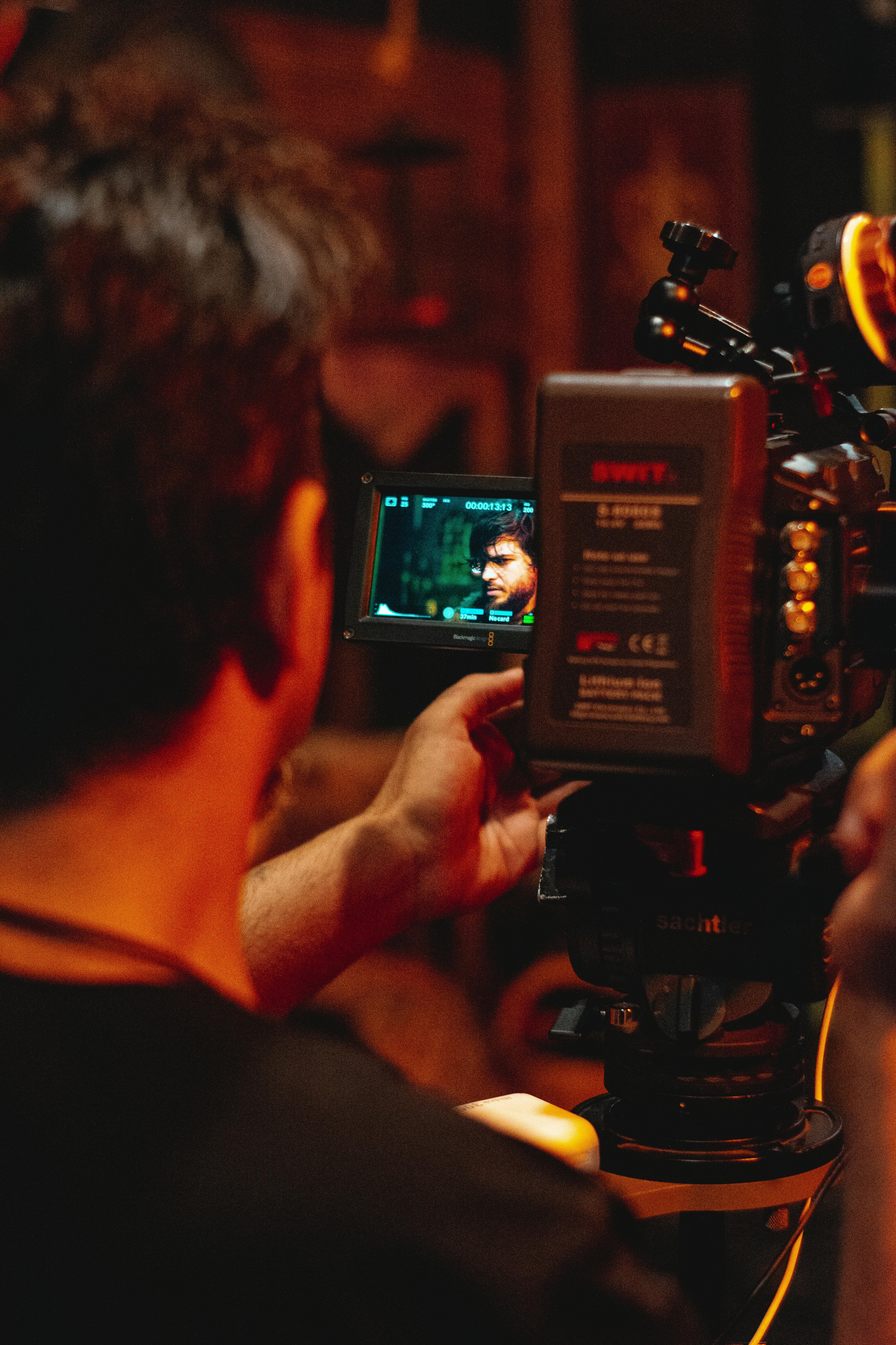 Free A cinematographer in action, adjusting a camera to capture a scene on a film set. Stock Photo