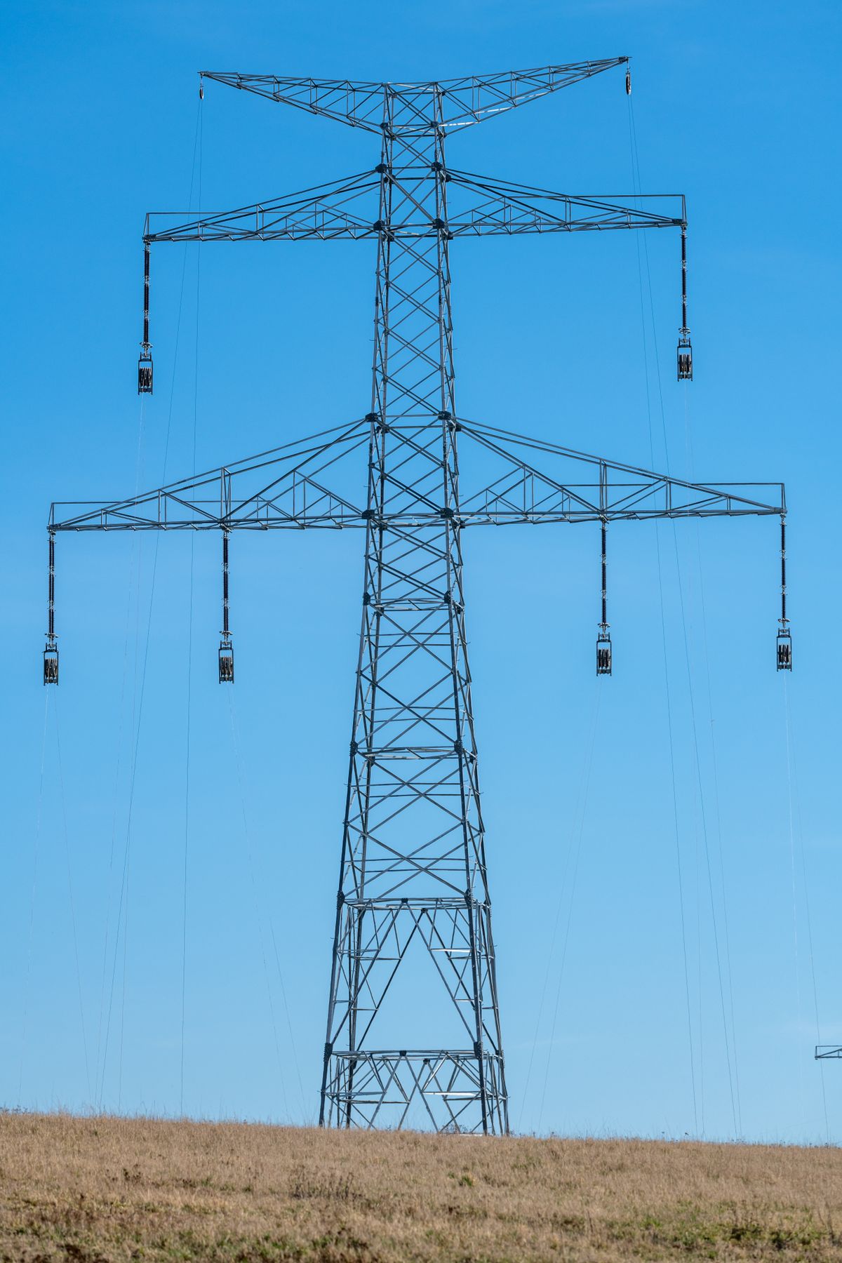 Electricity pylon standing in a vast open field, part of the Bulk Power System whose reliability risk is assessed in a self-report