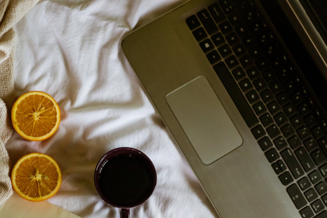 Oranges and a Laptop on a Bed