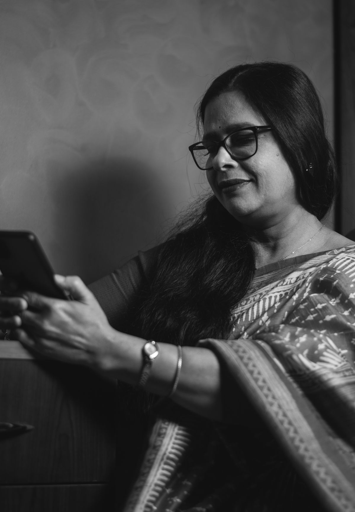 Indian woman in a saree smiling while using a smartphone