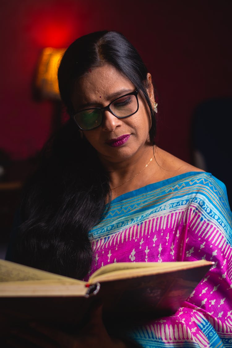 Brunette Woman In Blue And Purple Ornamented Saree Reading A Book