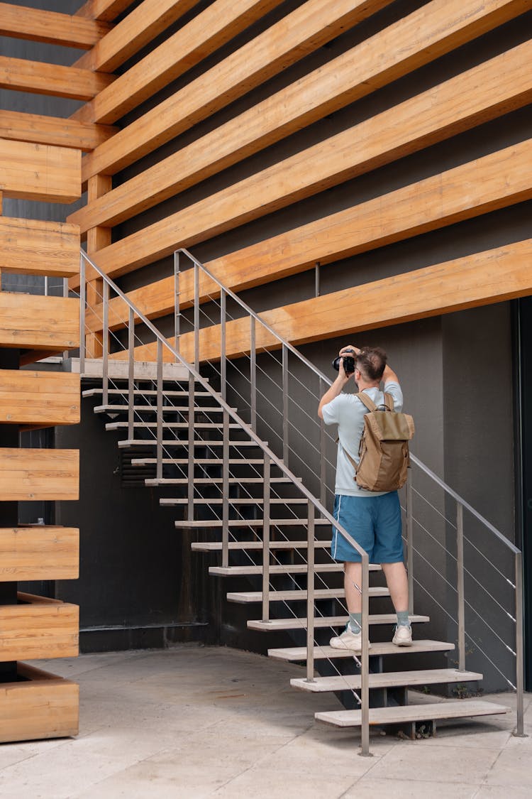 A Man With A Camera Standing On A Staircase