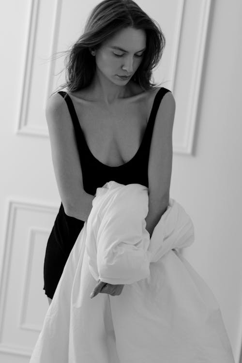 Black and White Photo of a Woman in Black Bodysuit with a Duvet in her Hands