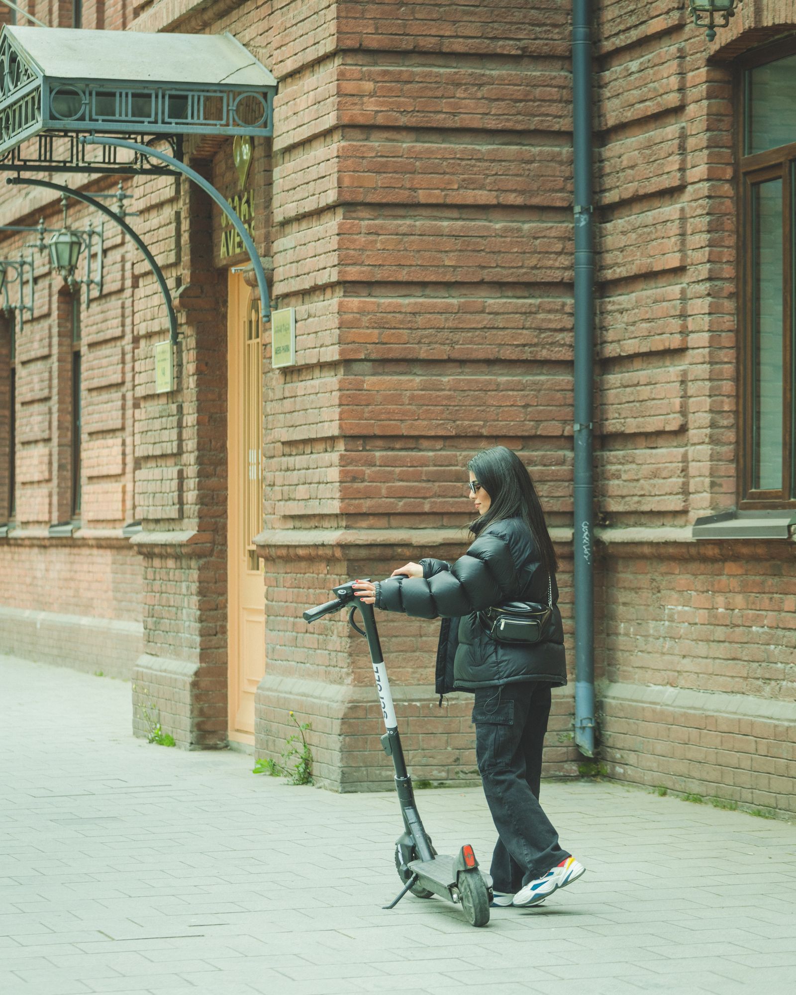 A woman standing next to a shared electric scooter on a city street