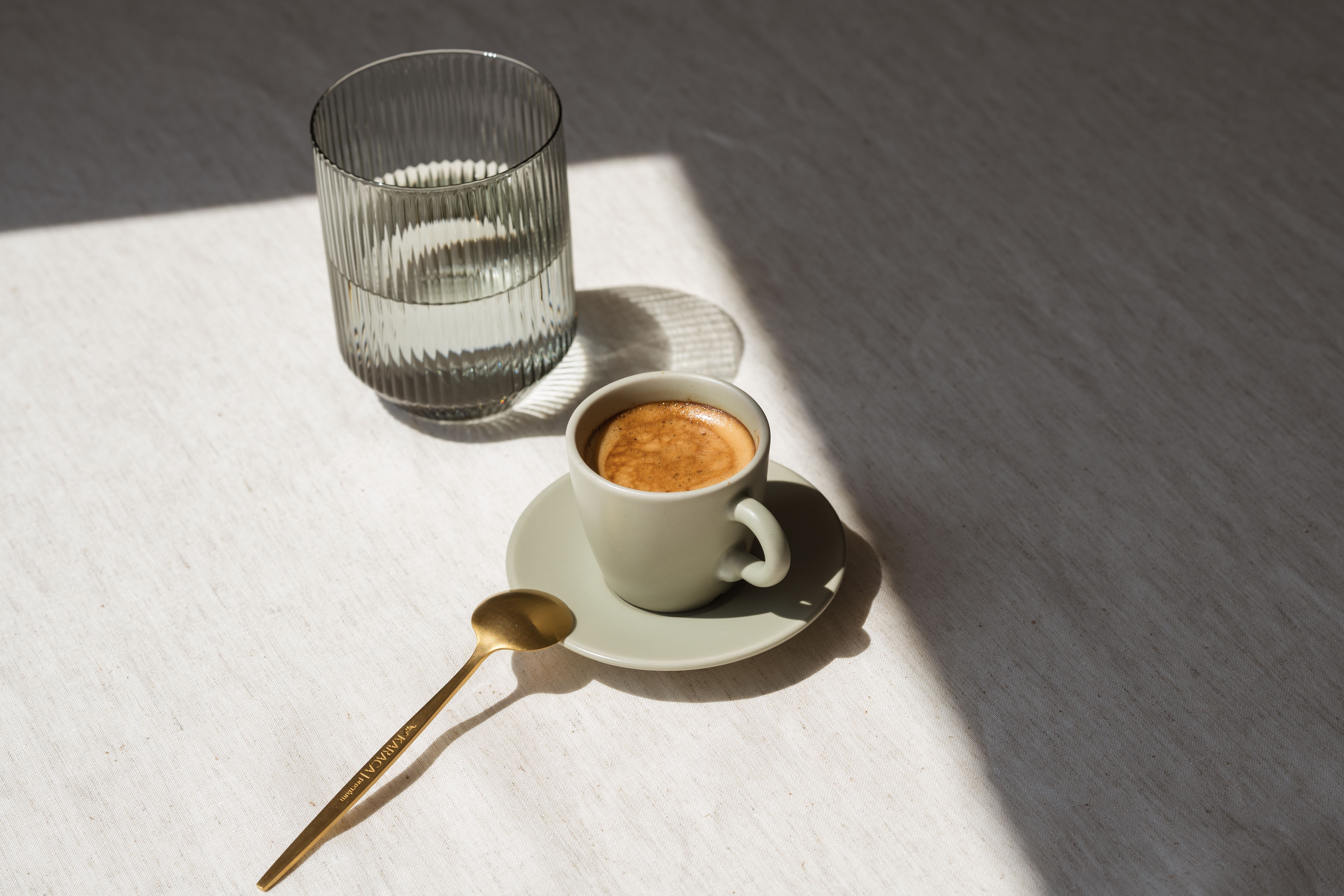Espressokopje met glas water op een linnen tafelkleed in zonlicht