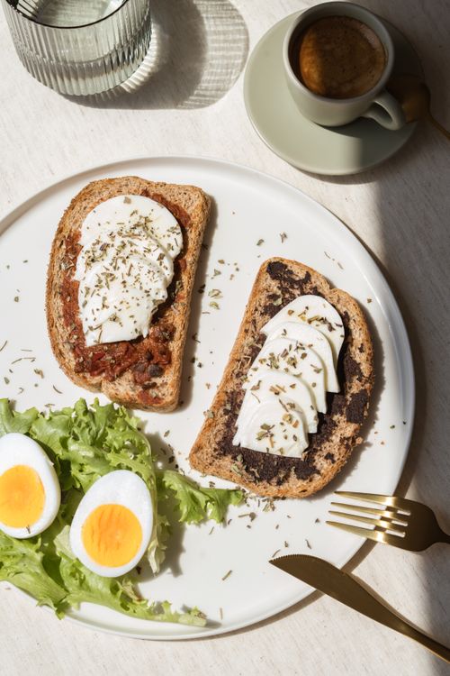 Free Delicious breakfast setup featuring gourmet toast with cheese and boiled eggs, ready to be served. Stock Photo