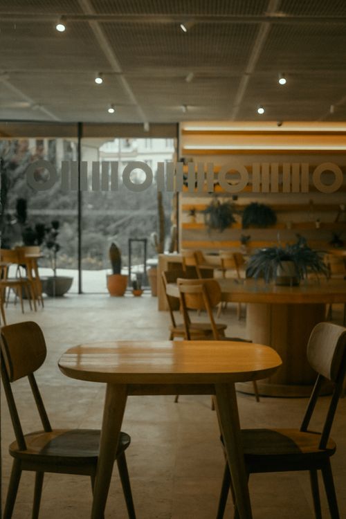 Free Stylish bistro interior featuring wooden tables and chairs, ideal for dining and relaxation. Stock Photo