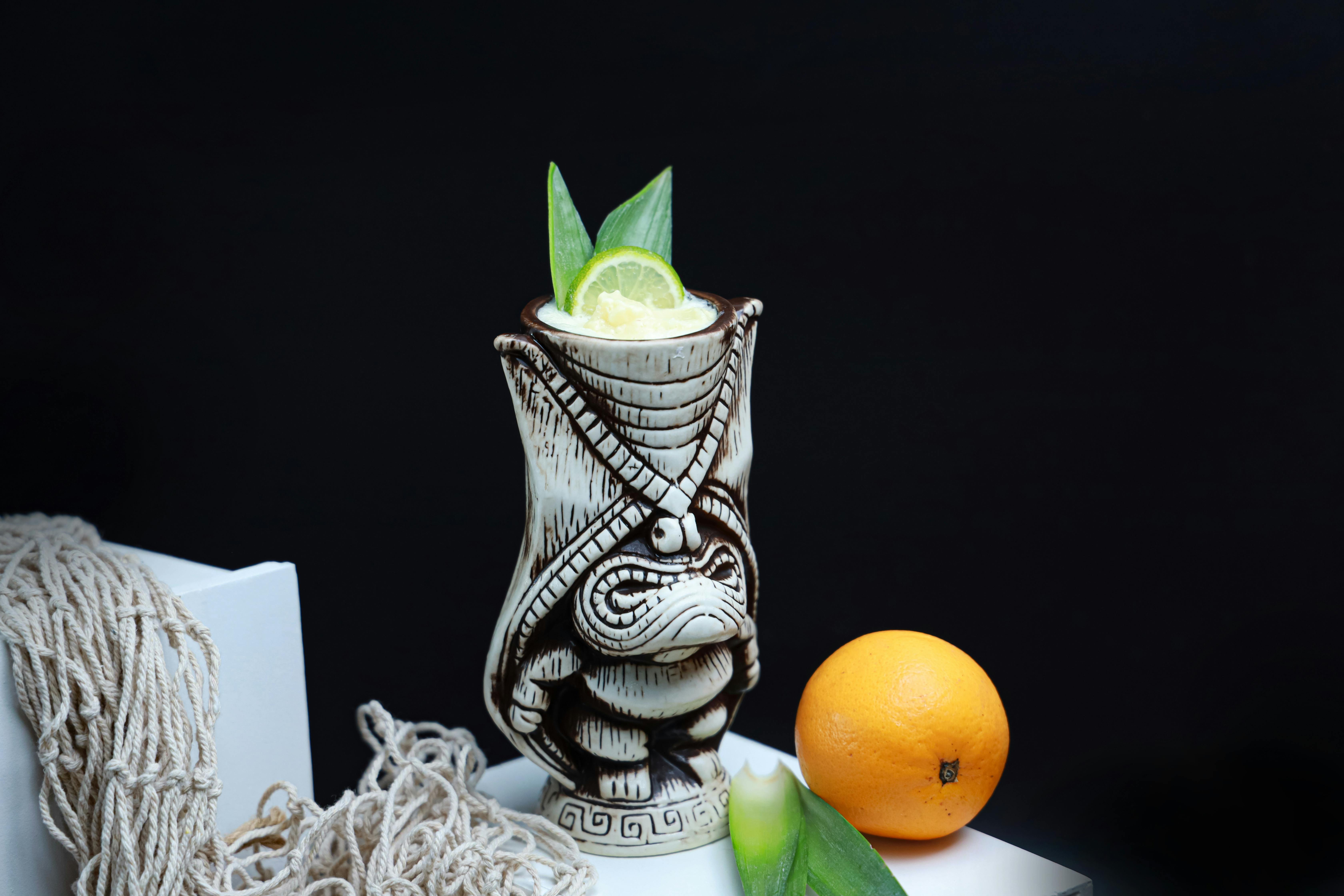 a tiki like drink with a lime and a slice of orange