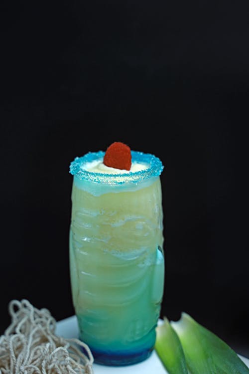 A blue and green drink with a straw and a garnish