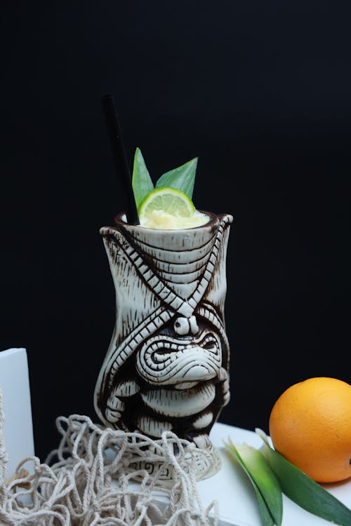 A drink with a tiki mask on it and a lime