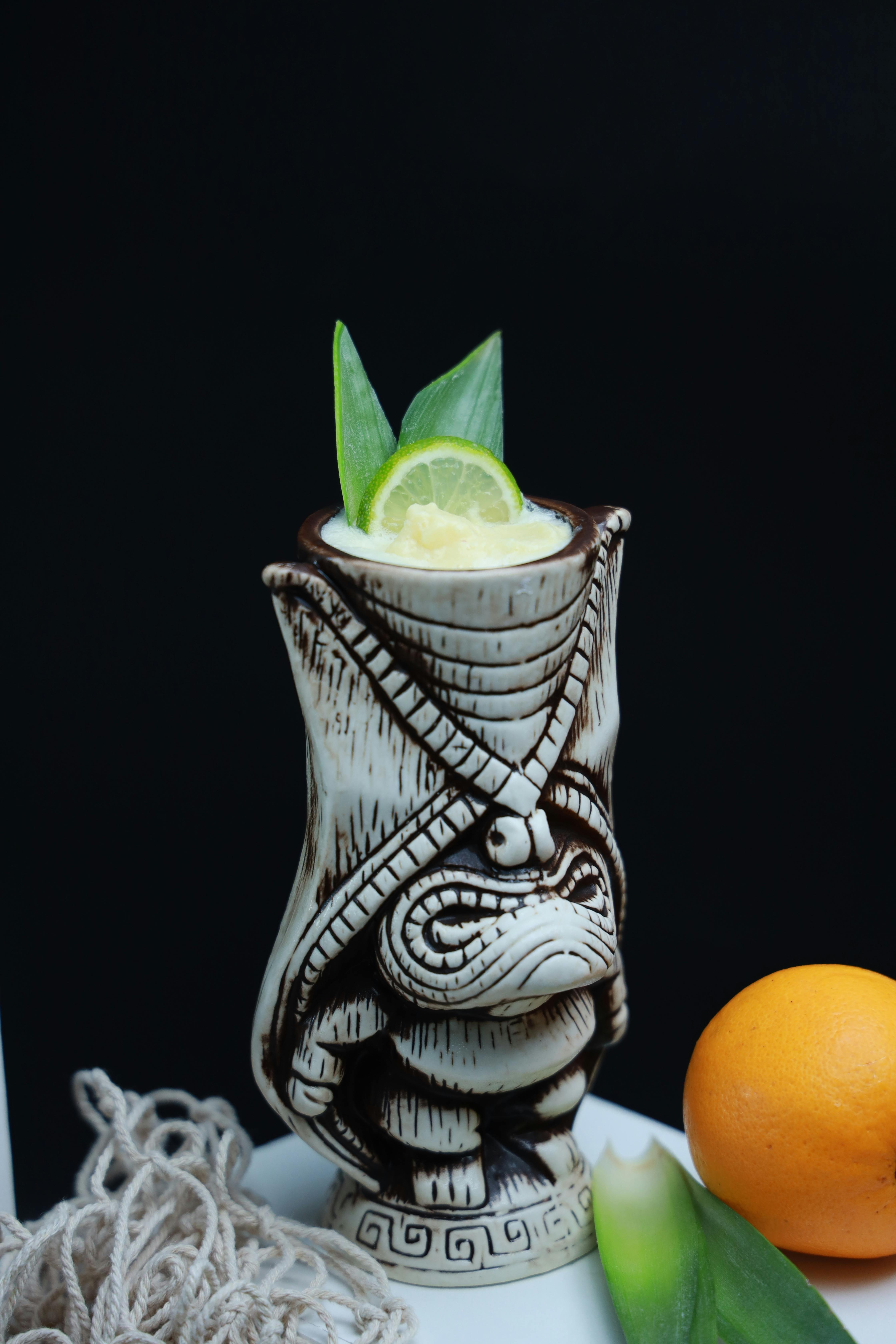 a tiki mug with a lime and orange slice