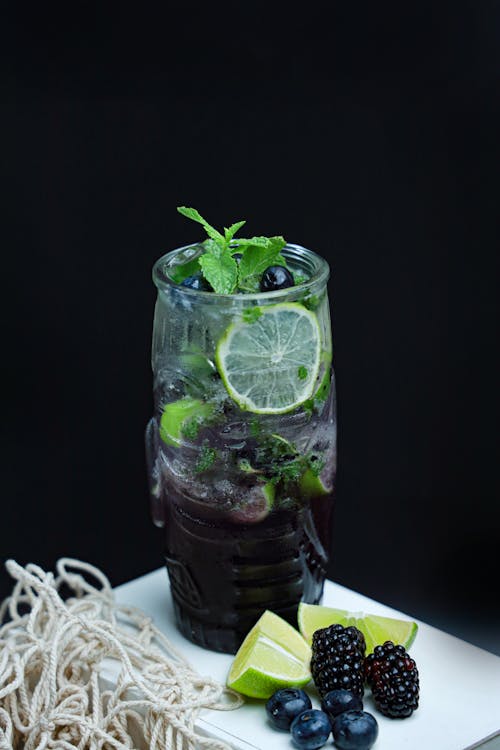 A glass of blueberry and lime drink with mint leaves