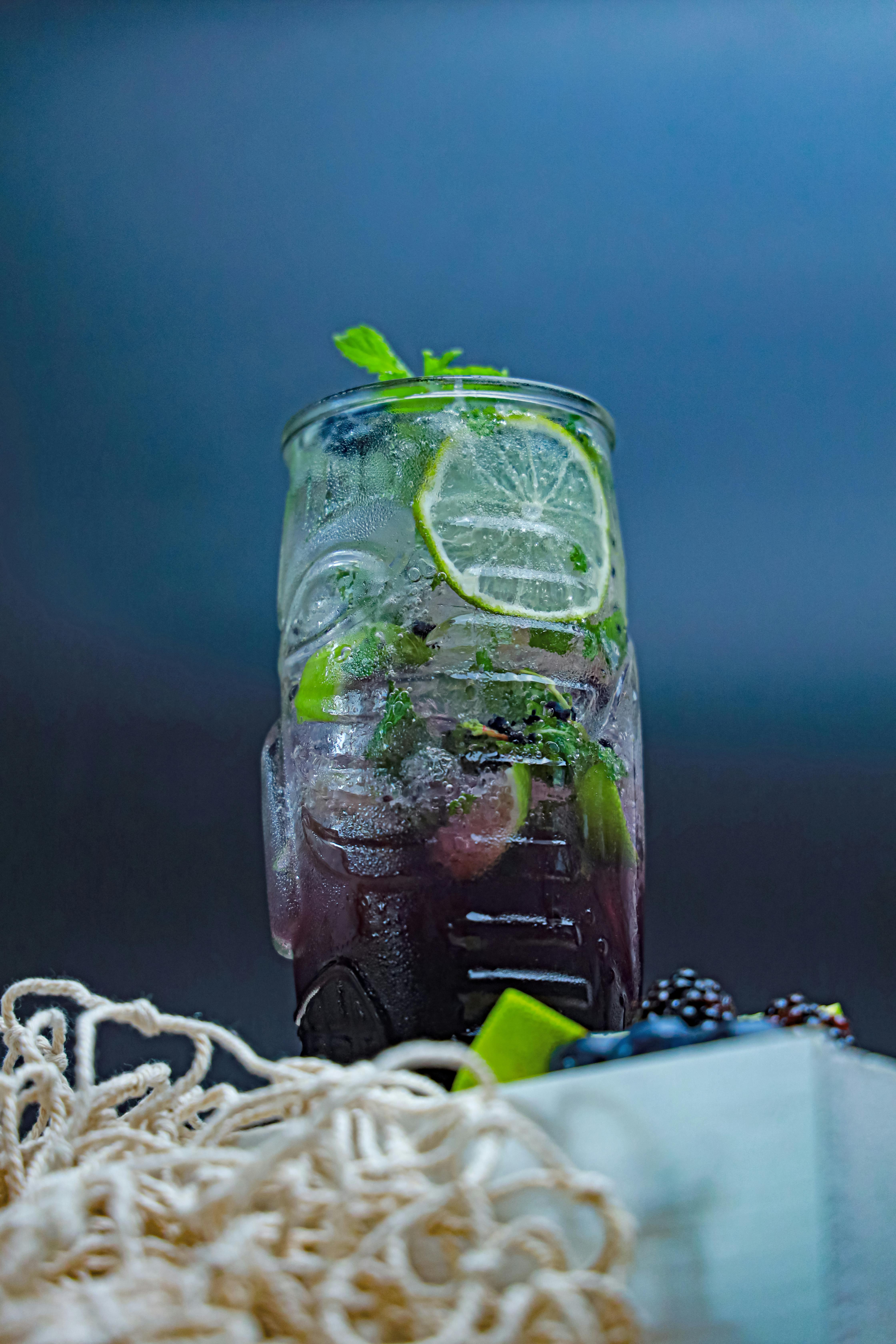 a glass of blackberry and lime drink with mint