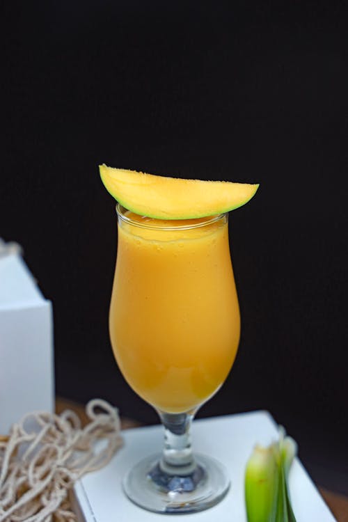 A glass of mango juice with a slice of lime