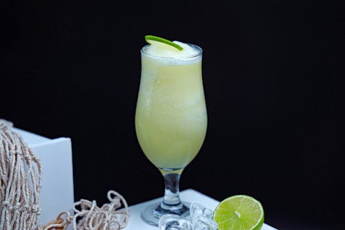 A glass of limeade with lime slices and a lime wedge