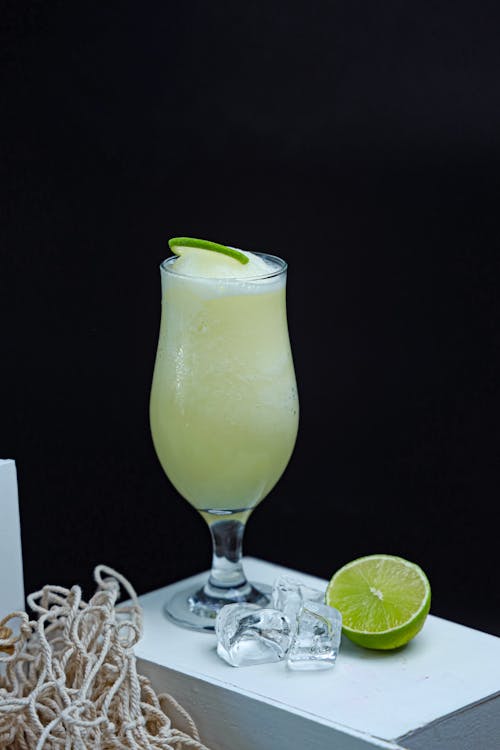 A glass of limeade with ice and lime slices