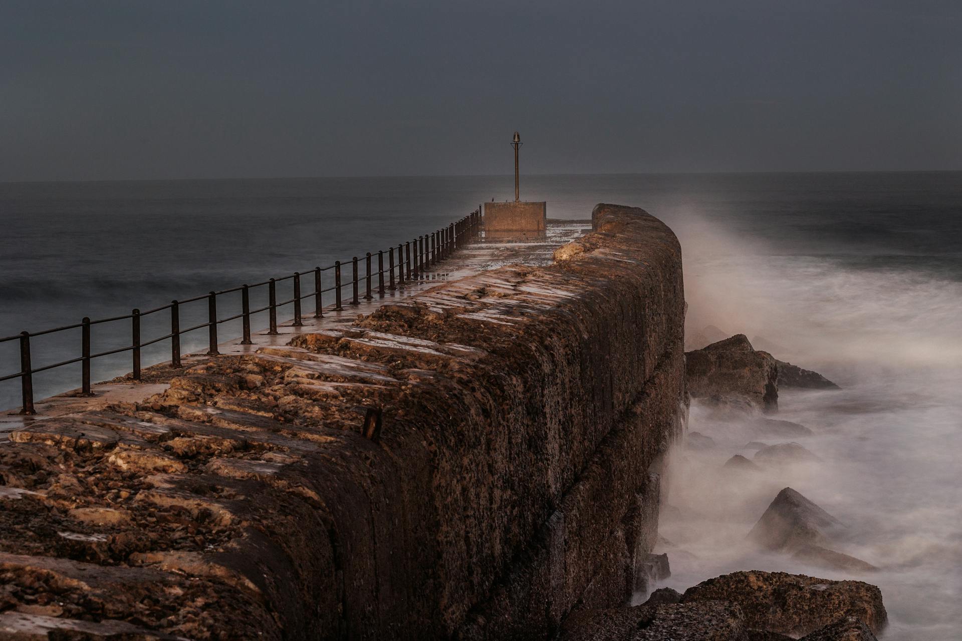 Strong waves crash against the pier wall in Port Alfred, showcasing dramatic weather and seascape.