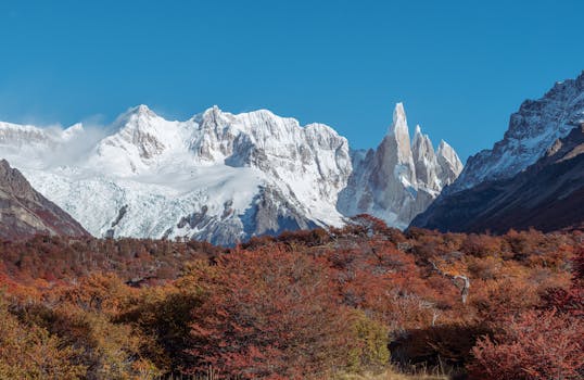 Breathtaking view of rugged snowcapped peaks and autumn foliage, perfect for nature lovers.