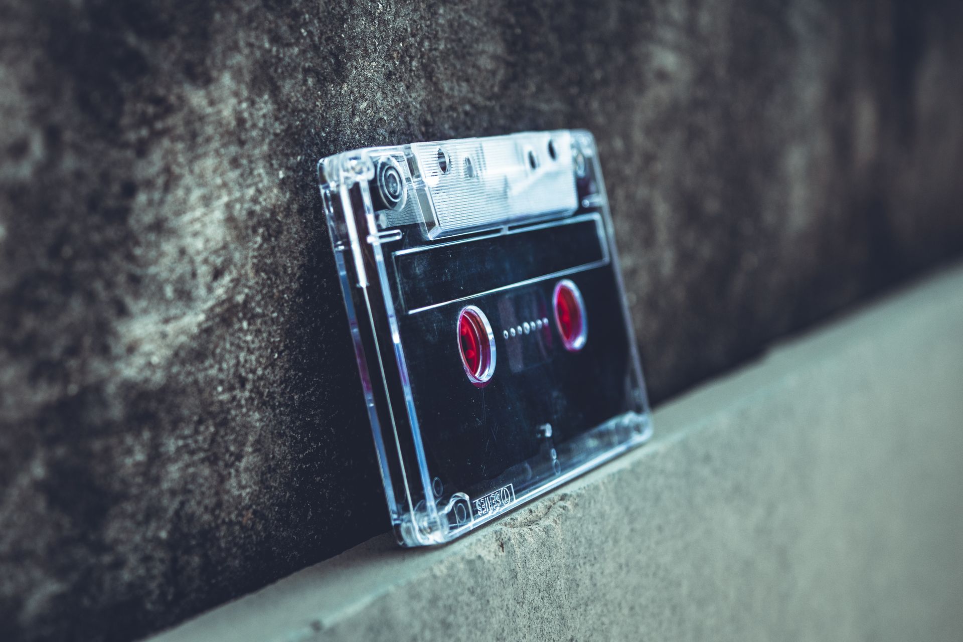 Close-up of a vintage cassette tape resting on a concrete surface, highlighting nostalgic audio technology.