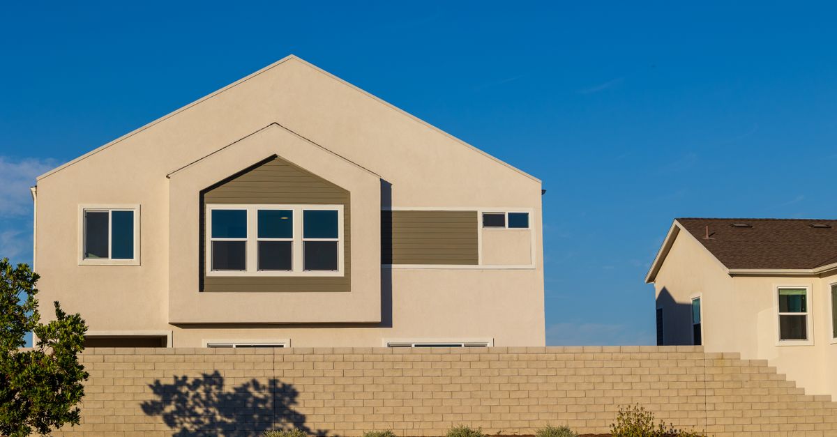 A modern suburban house with a sunlit facade against a clear blue sky.