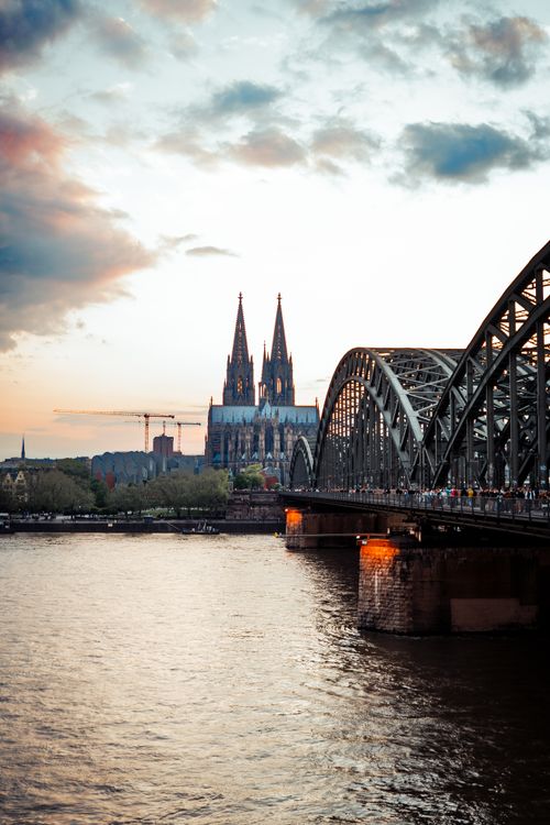 Free Stunning view of the Cologne Cathedral and Hohenzollern Bridge over the Rhine River at sunset in Cologne, Germany. Stock Photo