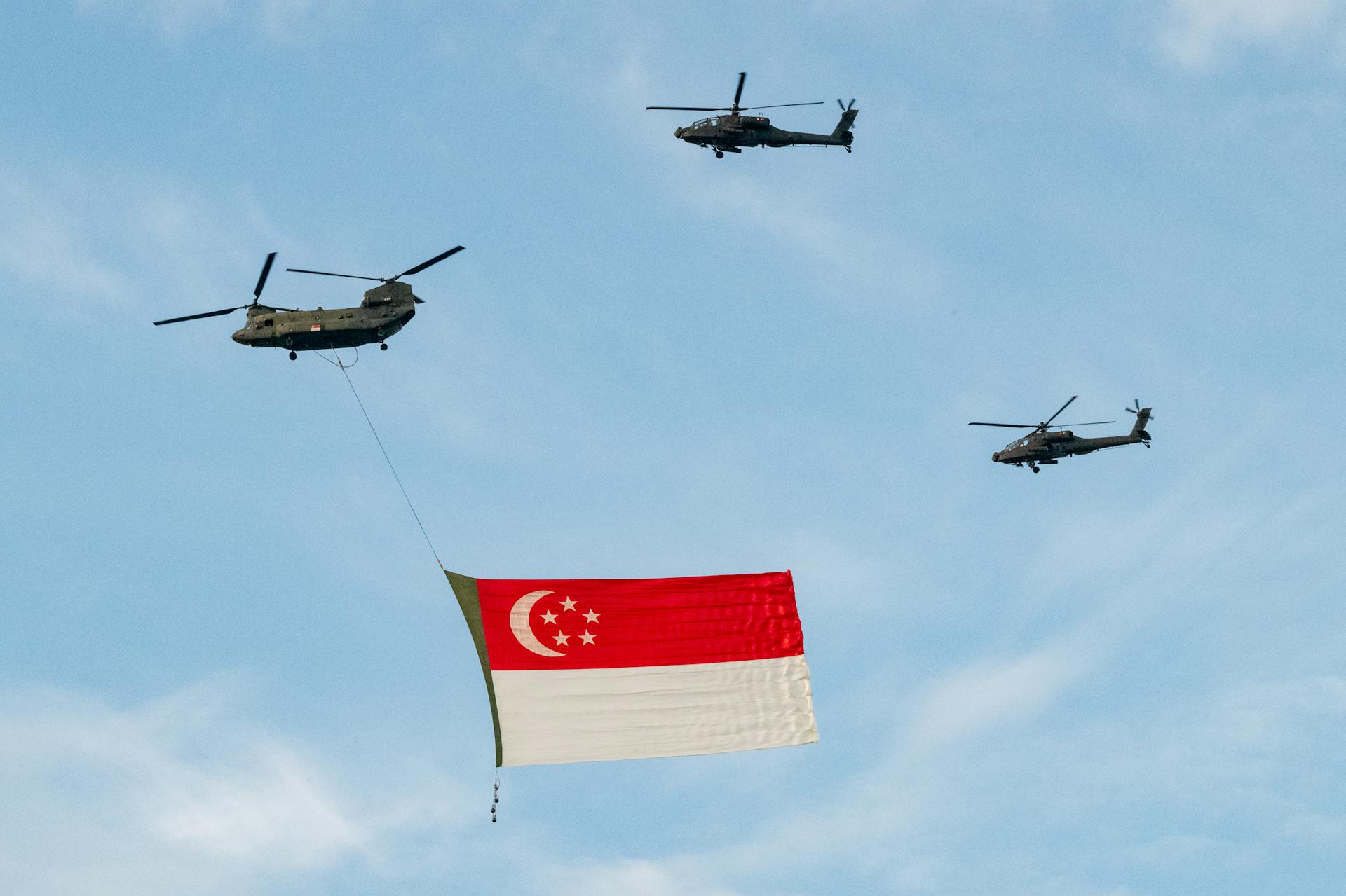 Vue des hélicoptères CH-47 Chinook et AH-64 Apache volant sous le drapeau de Singapour