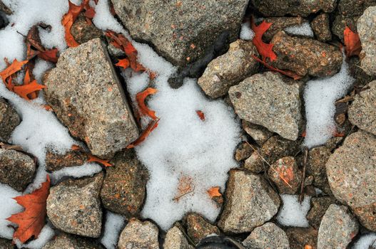A close-up view of snow-covered rocks interspersed with red autumn leaves, showcasing the transition between seasons., free online jigsaw puzzle on JigsawPuzzlesFreeOnline.org