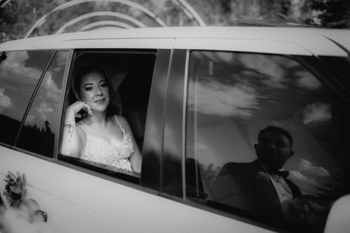 Free Elegant black and white photo of newlyweds in a car, featuring beautiful reflections and wedding attire. Stock Photo