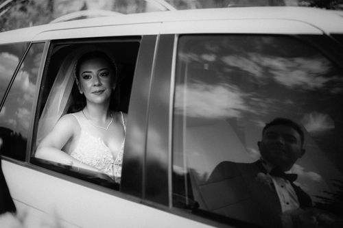 Free A bride and groom share a reflective moment in a car, captured in black and white. Stock Photo