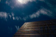 在云层和阳光映衬的黑暗天空中，现代建筑呈现低角度视图