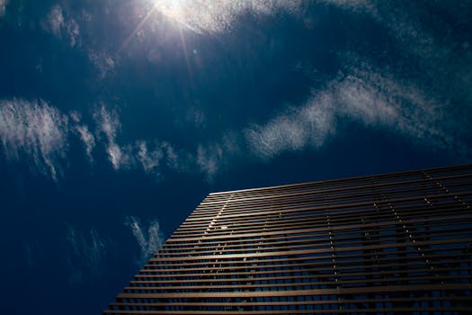 在云层和阳光映衬的黑暗天空中，现代建筑呈现低角度视图