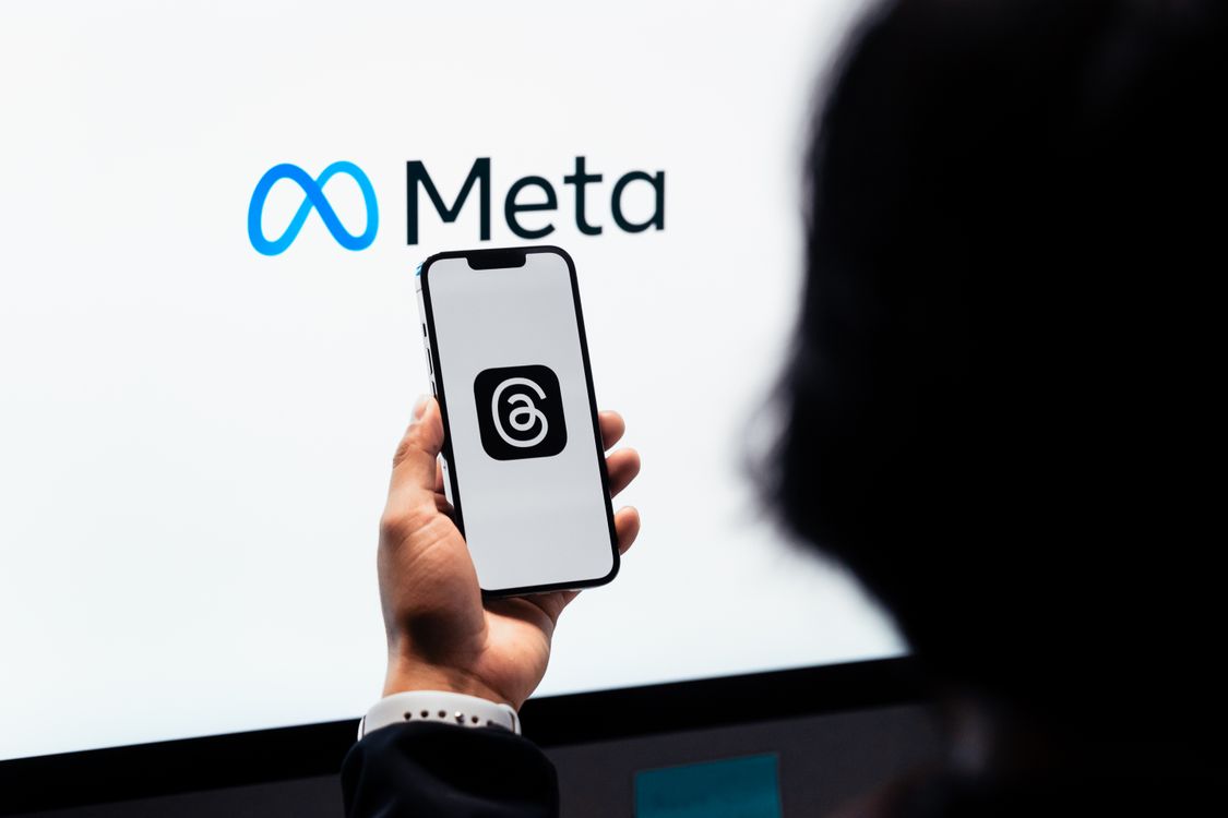 Ruke drže pametni telefon s Threads logotipom, Meta brend u pozadini