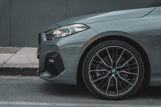 Detailed view of a grey luxury car's front fender and wheel, parked on an urban street.