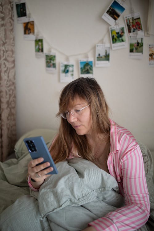 Woman Sitting with Cellphone in Bed