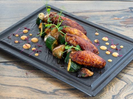 Delicious grilled chicken wings paired with sauteed zucchini and potatoes, garnished with sprouts.