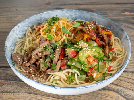 A vibrant bowl of vegan spaghetti topped with fresh vegetables for a healthy meal.