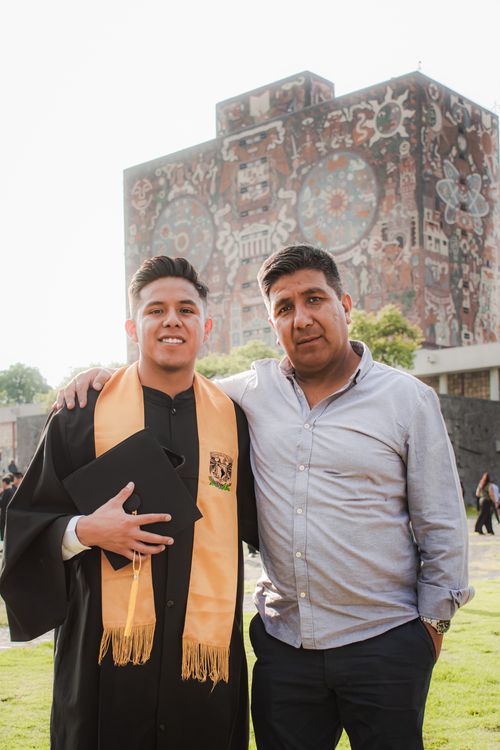 Free Father and son celebrating graduation in front of UNAM library mural, Mexico City. Stock Photo