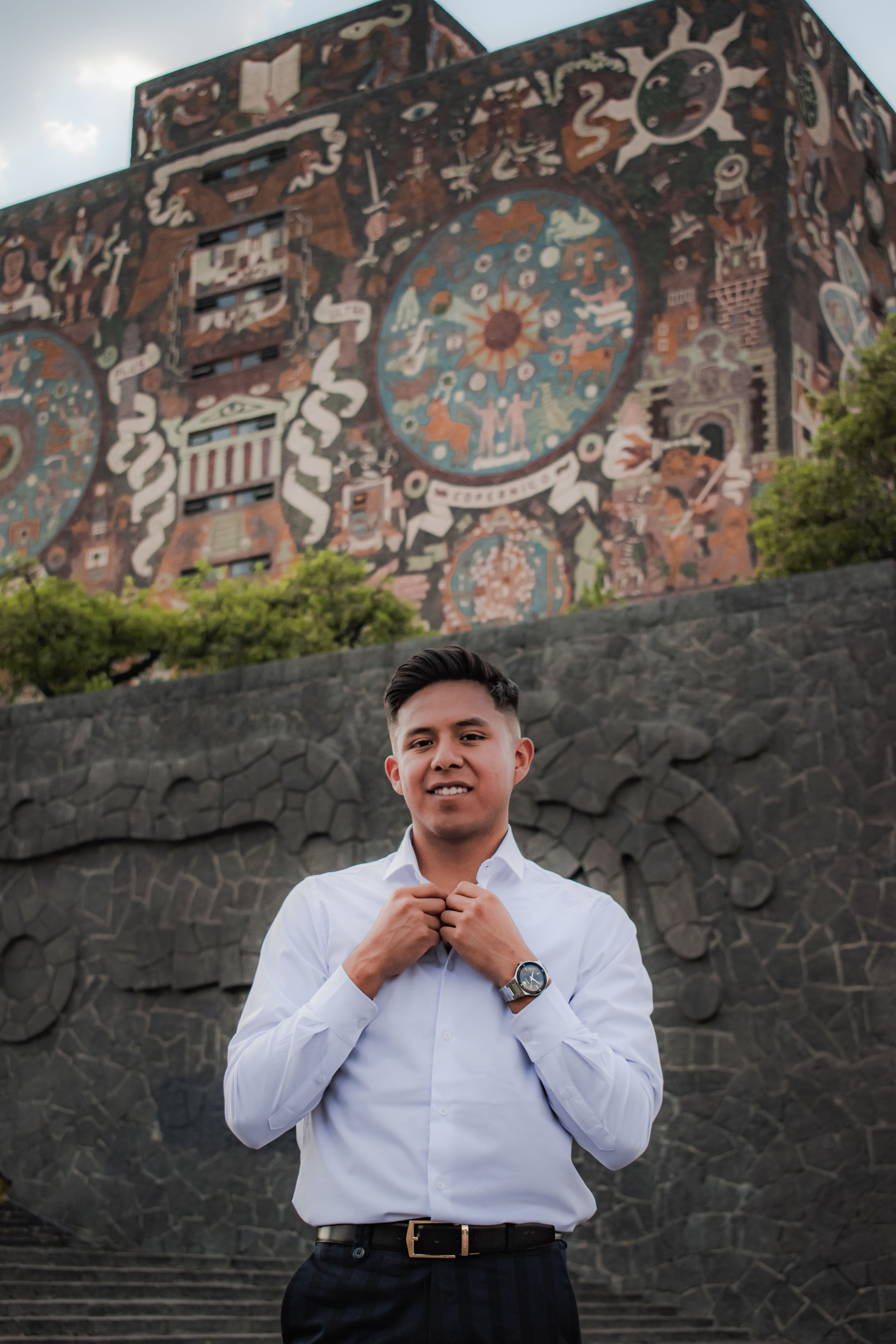 Portrait of a man adjusting his shirt in front of the Central Library at UNAM, Mexico City.