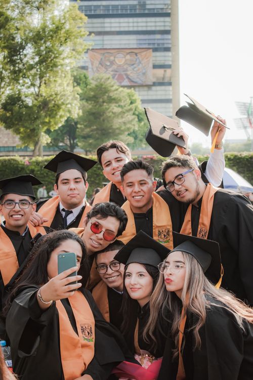 Free Group of multicultural graduates taking a selfie outdoors celebrating their achievement. Stock Photo
