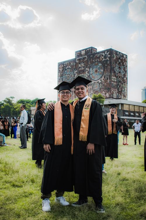 Free Two graduates in caps and gowns celebrate outdoors on a university campus in Mexico. Stock Photo