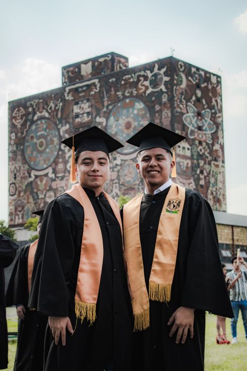 Free Two young graduates in caps and gowns smiling in front of a public building in Mexico City. Stock Photo
