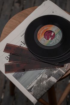 A nostalgic still life with a vinyl record and film negatives on a wooden table.