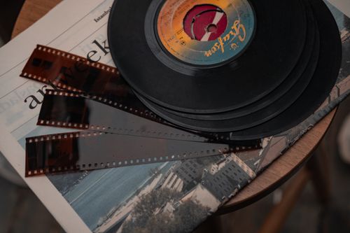 Free Stack of vintage vinyl records and film negatives on a wooden table. Stock Photo