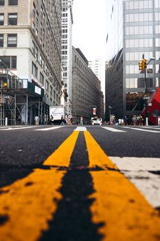 Dynamic city street scene featuring skyscrapers and urban life with prominent yellow road lines.