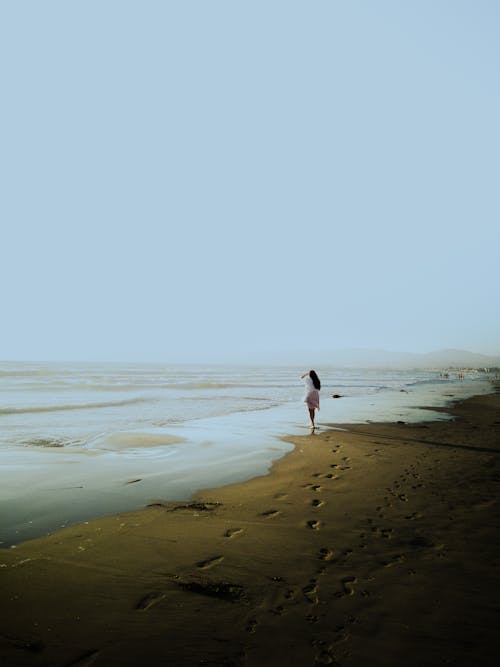 Free Footprints on the Wet Beach Sand of a Tourist Walking by the Sea Stock Photo