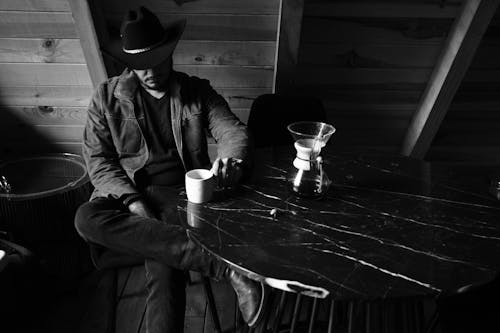 Man in Hat and Jacket Sitting with Cup