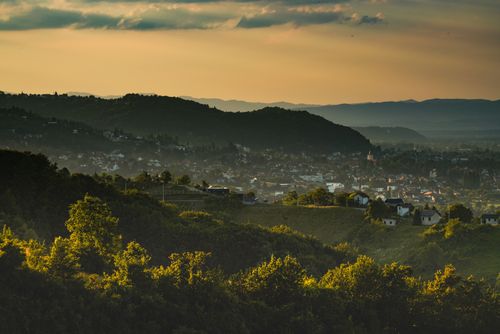 Free A serene landscape featuring a town nestled in hills, bathed in warm, golden sunset light. Stock Photo