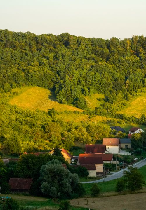 Free Charming countryside village nestled in lush green hills under a warm summer's day. Stock Photo